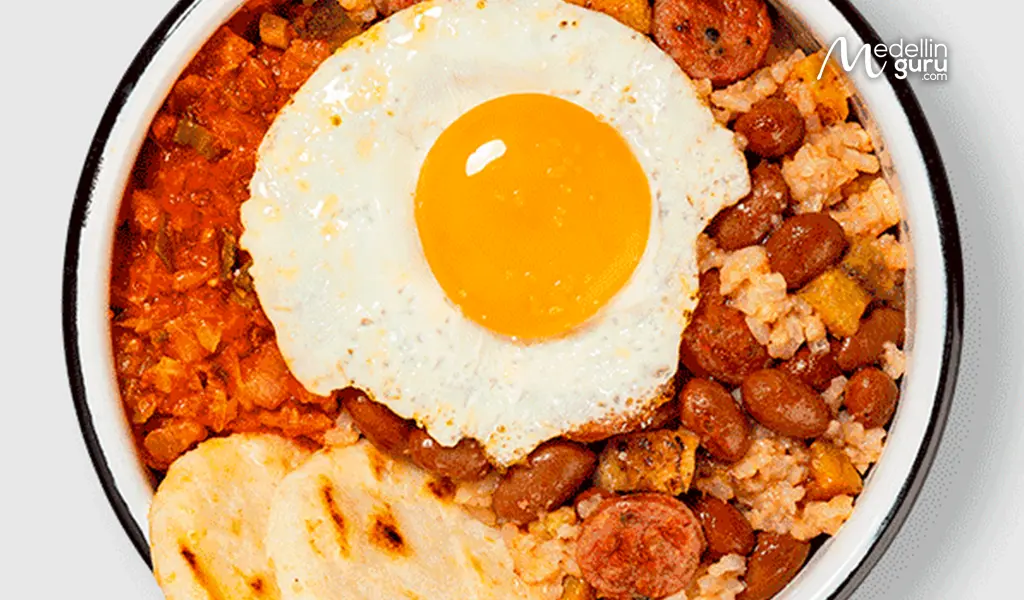 Authentic Paisa breakfast plate with calentado, arepa con queso, and chicharrón in Medellín, Colombia