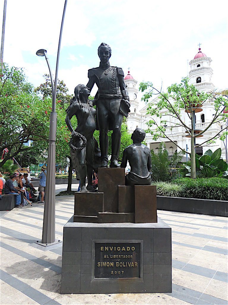 Statue of Simon Bolivar in Parque Envigado with Iglesia de Santa Gertrudis in the background