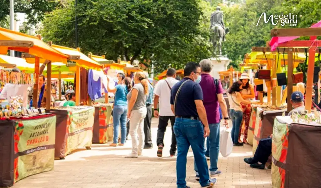 Shoppers browsing colorful artisan stalls at Mercado de Sanalejo in Medellín, Colombia, an outdoor market known for handmade leather goods