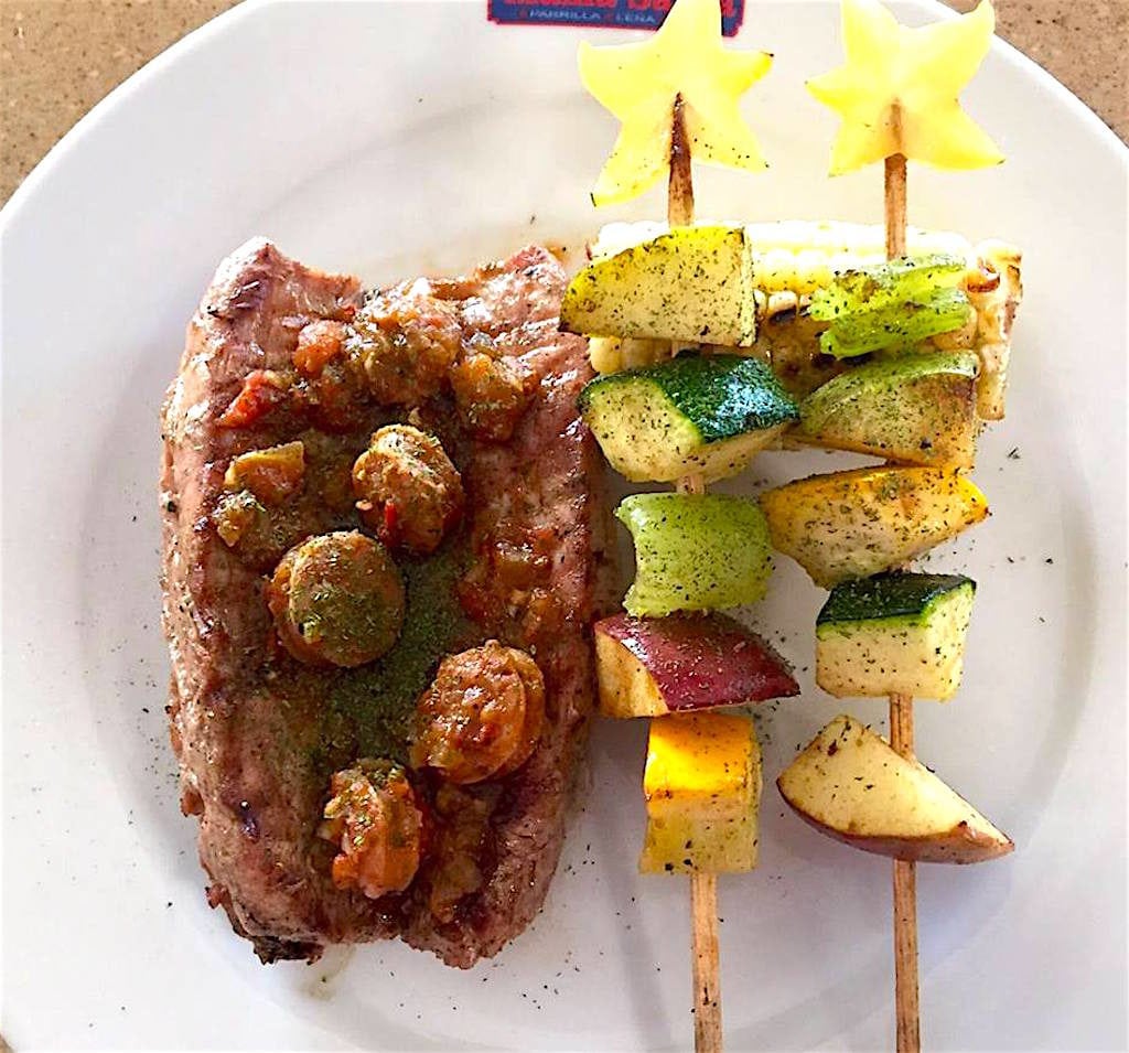 Sirloin steak with pork sausage and roasted corn with skewers of vegetables and fruits, photo courtesy of Mama Santa