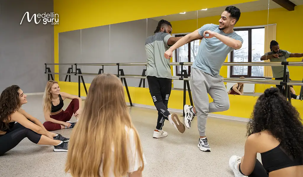 A salsa dance instructor praising a student with '¡La tenés clara con el ritmo!' during a class in Medellín.
