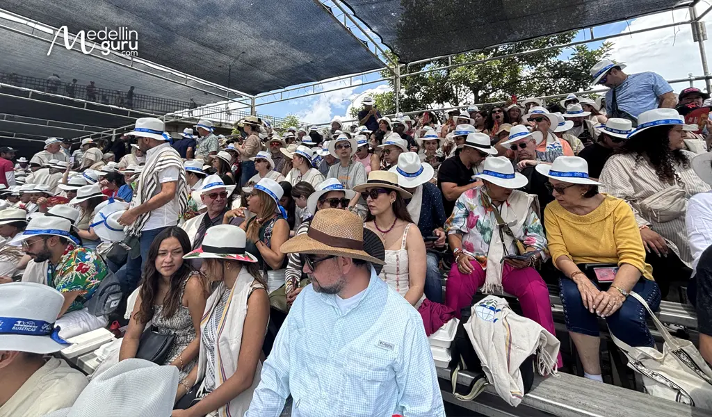 Spectators in a crowded grandstand under a sunshade at the Desfile de Silleteros 2025.