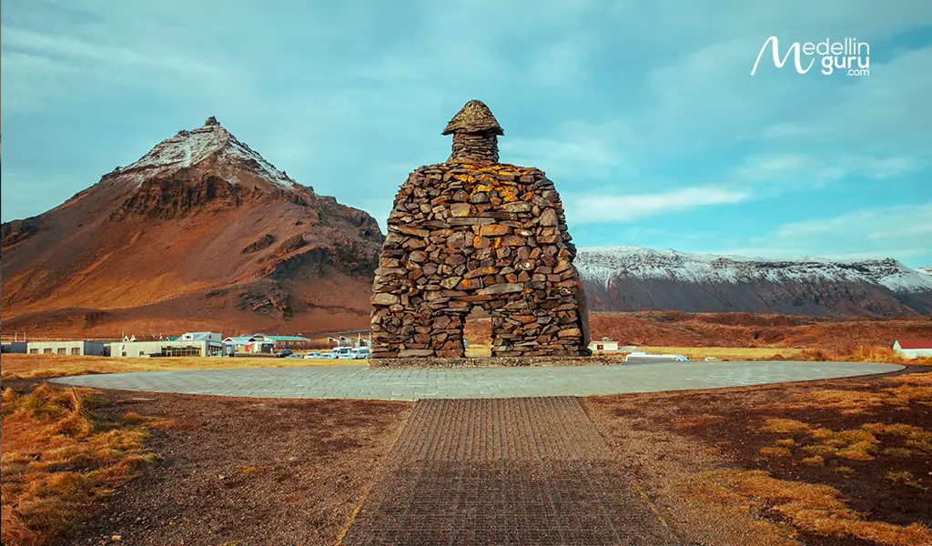 Bárður Snæfellsás stone monument in the coastal village of Arnarstapi, with the mountains of the Snæfellsnes Peninsula in the background.
